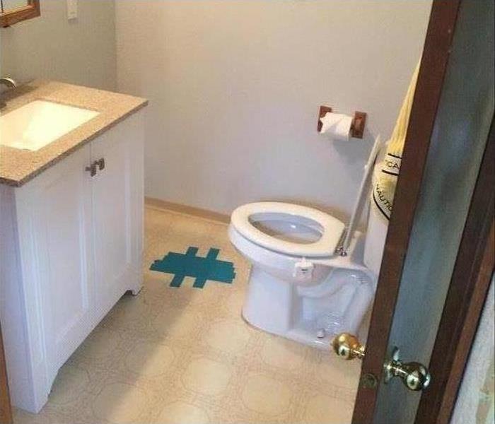 The same bathroom completely restored with new flooring, paint, vanity and toilet in place.